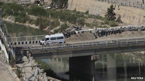 An ambulance crosses over a bridge where barricades and sandbags were piled as protection from snipers loyal to Syria's President Bashar al-Assad