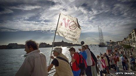 Protesters line the the bank of the Giudecca Canal during a demonstration to block a cruise ship