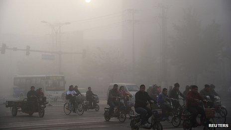 Residents ride bicycles along a street amid heavy haze in Xingtai, Hebei province, on 3 November 2013