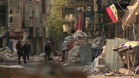 A wrecked car and destroyed building fronts in the neighbourhood of Tadamon in south east Damascus