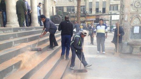 Men sweeping away the debris after mortar attack on the Hijaz railway station