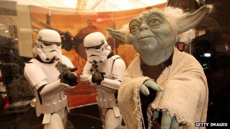 Stormtroopers from the Star Wars series of films looking at a model of Yoda