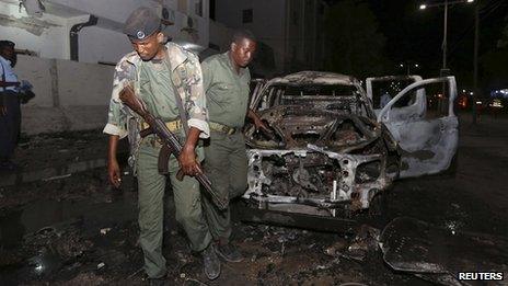 Somali policemen inspect the scene of an explosion outside the Maka Al-Mukarama hotel in Somalia's capital Mogadishu (8 November 2013)