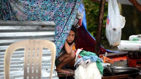 A young girl shelters under a makeshift awning in the aftermath of Typhoon Haiyan in Tacloban in the Philippines