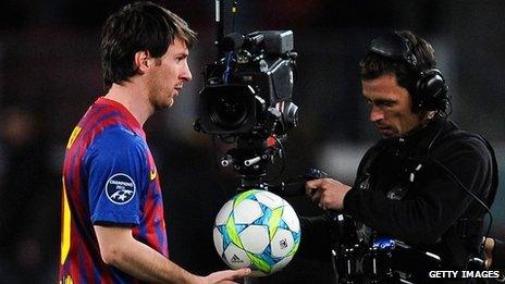 Barcelona's Lionel Messi leaves the pitch after a Champions League game, followed by a cameraman