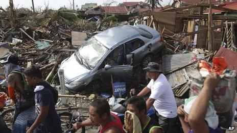 Survivors in Tacloban move past houses and vehicles destroyed by Typhoon Haiyan