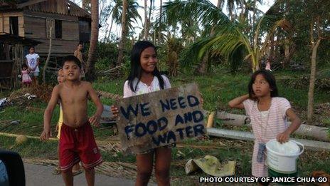 Children on the way to northern Cebu holding up a sign saying "We need food and water"