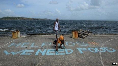 A man paints a message on a basketball court that reads "Help SOS We Need Food" at Anibong in Tacloban, eastern island of Leyte on 11 November 2013