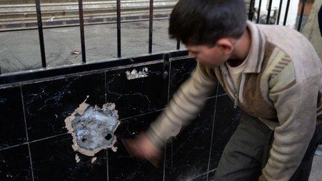 A Pakistani youth looks at a bullet-riddled wall of an Afghan bakery where Nasiruddin Haqqani, a senior leader of the feared militant Haqqani network, was assassinated in the Bhara Kahu area on the outskirts of Islamabad (photo: November 11, 2013).