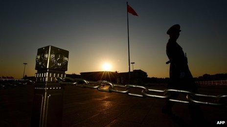 A Chinese paramilitary officer patrols Tiananmen Square in front of the Great Hall of the People (background) after the Communist Party Central Committee concluded its secretive Third Plenum in Beijing on 12 November 2013