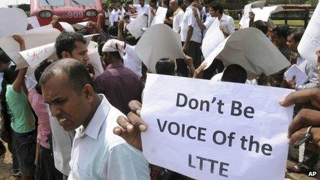 Sri Lankans hold placards while blocking a train carrying Channel 4 journalist Callum Macrae