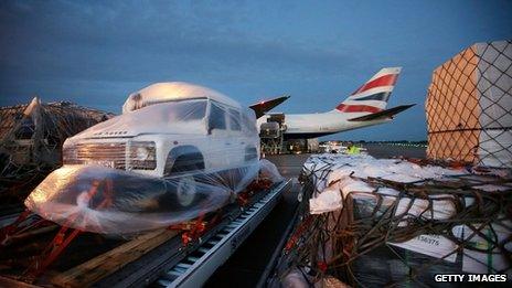 Supplies and equipment including a jeep on a runway ready to be loaded onto a plane