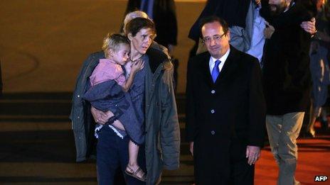 French President Francois Hollande (front R) speaks to Albane Moulin-Fournier carrying one of her children as the seven members of the Moulin-Fournier family arrive from Yaounde, at the Orly airport, near Paris (20 April 2013)