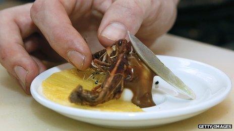 A plate of pineapple served with some grasshoppers on top