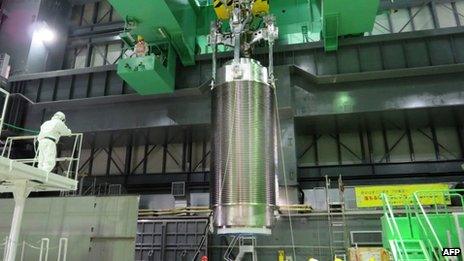 This handout picture taken by Tokyo Electric Power Co (Tepco) on 13 November 2013 shows a cask of nuclear fuel being lifted and moved by Tepco workers during an exercise to remove fuel rods from a pool at the unit four reactor building of Tepco's Fukushima Dai-ichi nuclear plant in the town of Okuma in Fukushima prefecture