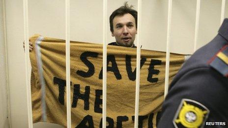 Greenpeace activist Tomasz Dziemianczuk of Poland shows a banner inside a defendants' cage during a court session in St Petersburg, November 19, 2013