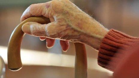 An elderly woman's hand on a stick