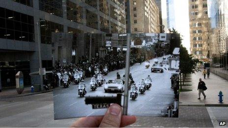 A 21 November 1963 photo of John F Kennedy's motorcade is held up over a 7 November street scene in Houston, Texas