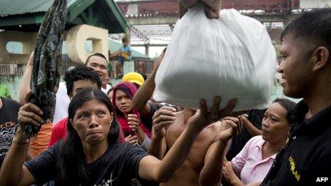 A woman receives a food parcel at a temporary shelter for super typhoon Haiyan victims in Tacloban on November 22, 2013