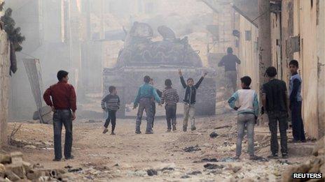 Children run after a tank driven by fighters from the Tawhid Brigade, in Aleppo, November 11, 2013