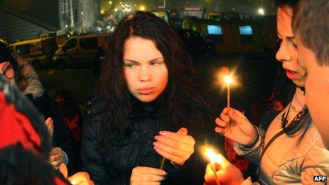 People carry a candles at the scene of the disaster