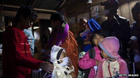 A boy wears a mask as people await transport to a temporary evacuation centre following another eruption of Mount Sinabung at Sigarang Garang village on 24 November 2013 in Karo district, North Sumatra, Indonesia