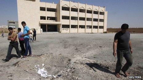 Syrians inspect the aftermath of an air strike on a secondary school in Raqqa (29 September 2013)