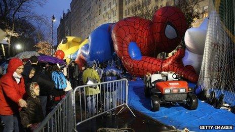 Sightseers photograph giant balloons the evening before the Macy's Thanksgiving Day Parade in New York City on 27 November 2013