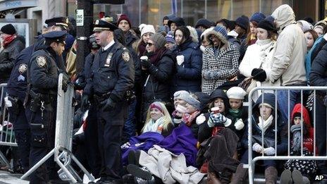 New York police officers adjust a barricade as people wait in cold weather along the route of the Macy's Thanksgiving Day Parade on 28 November 2013