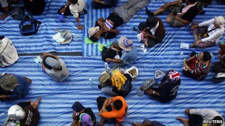 An anti-government protester sleeps among others sitting on the road outside the national police headquarters where they are protesting in Bangkok on 28 November 2013