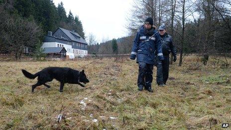 Police with a sniffing dog investigate the area around a house near Reichenau, eastern Germany Friday Nov. 29, 2013