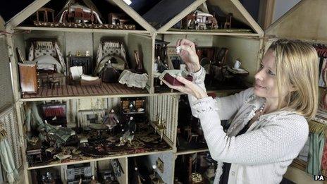 Woman examining some of the items in the dolls house