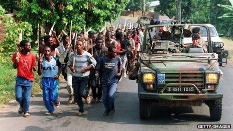 This file picture taken 27 June 1994 shows French soldiers on patrol passing ethnic Hutu troops from the Rwandan government forces, near Gisenyie