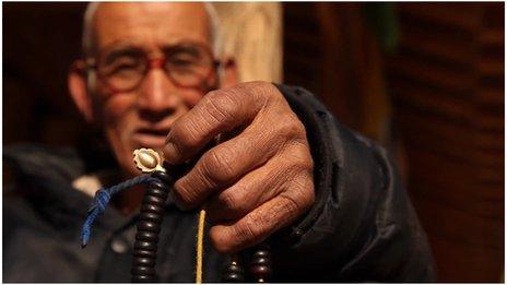 Tibetan man holding beads