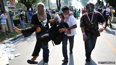 Men carry a fellow protester with a rubber bullet wound during a violent anti-government protest near Government House on 2 December 2013 in Bangkok, Thailand