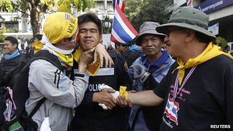 An anti-government protester kisses a riot police officer on the cheek during a rally outside the Government House in Bangkok on 3 December 2013