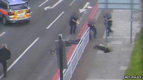 This image shows Michael Adebowale on the floor raising his gun