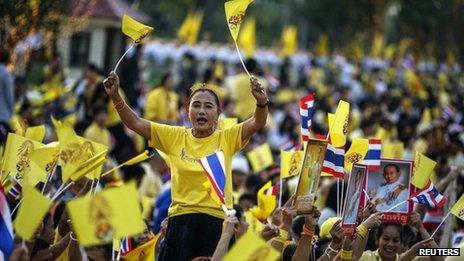 Well-wishers hold pictures of Thai King Bhumibol Adulyadej and wave Thai national flags as they gather to celebrate his 86th birthday near Klai Kangwon Palace, Hua Hin, Prachuap Khiri Khan province, 5 December 2013