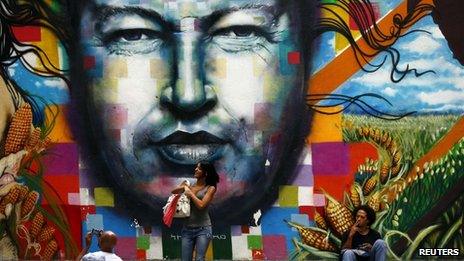 People stand around a mural depicting the late Venezuelan President Hugo Chavez in downtown Caracas on 23 September, 2013