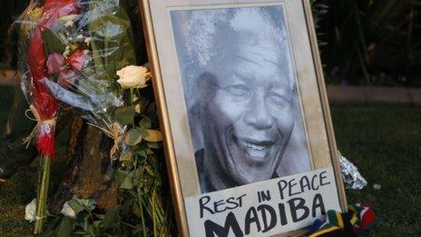 A framed portrait of former president Nelson Mandela and flowers are placed outside Mandela"s Johannesburg home Friday, Dec. 6, 2013 after the freedom fighter passed away Thursday night after a long illness. (