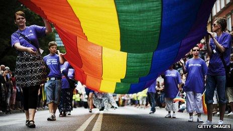 People unfurl a gay pride flag at the Stockholm Pride march