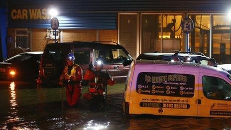 Coastguard rescue workers check vehicles in a flooded car wash during a storm surge in Great Yarmouth