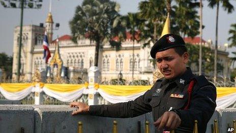 A Thai policeman stands next to concrete barricades outside the gates of the prime minister's office, known as Government House, in Bangkok, Thailand