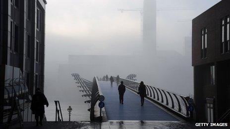 People walking through thick fog at the Millennium Bridge over the River Thames