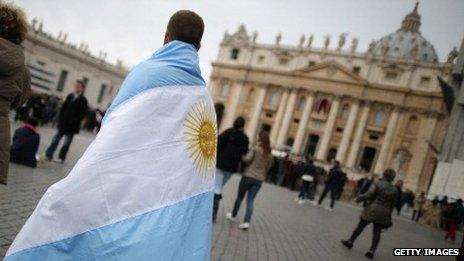 A boy walks in St Peter's Square, draped in the flag of Argentina