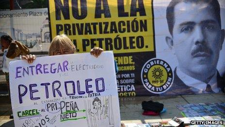 Protesters holding signs against privatising oil fields