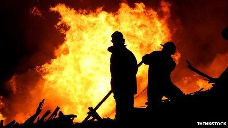 Fire fighters in front of fire at night