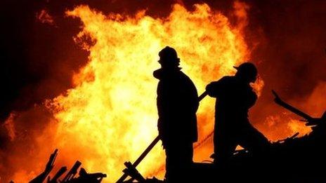 Fire fighters in front of fire at night