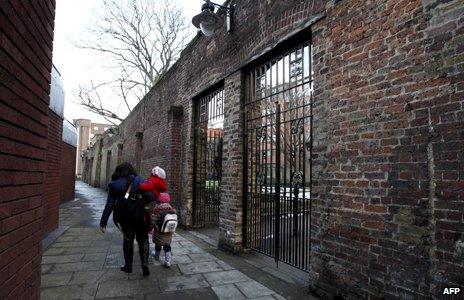 Woman and child walk past remaining wall of Marshalsea prison in London, 2012