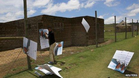 A man places a poster of Nelson Mandela on a fence at the perimeter of the former president's property in Qunu, on a blustery day.